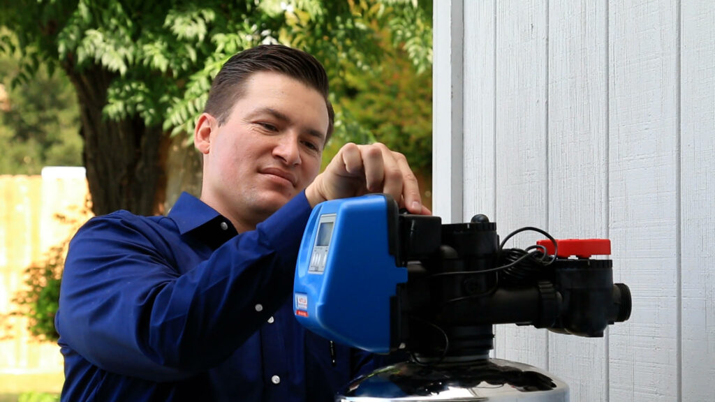 A man fixing a water softener in front of a house.
